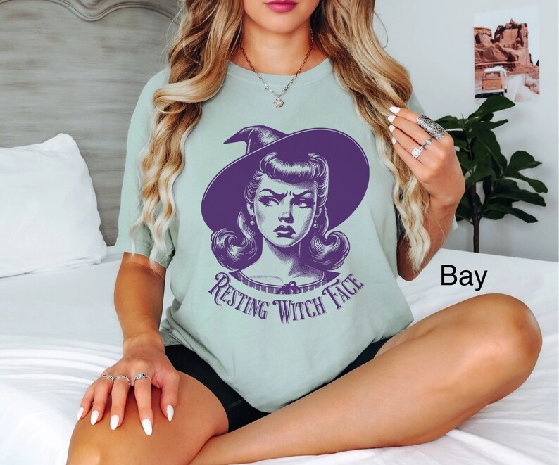 May include: A light green t-shirt with a purple witch graphic and the text "Resting Witch Face".