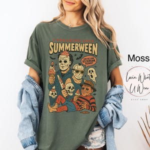 K&ouml;nnte beinhalten: Moosgr&uuml;nes T-Shirt mit einer Grafik, die Horrorfilmfiguren mit Eiswaffeln zeigt. Der Text lautet "SUMMERWEEN" mit einem gruseligen Thema. Das Shirt hat eine lockere Passform.
