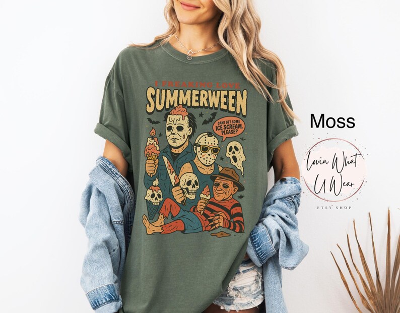 K&ouml;nnte beinhalten: Moosgr&uuml;nes T-Shirt mit einer Grafik, die Horrorfilmfiguren mit Eiswaffeln zeigt. Der Text lautet "SUMMERWEEN" mit einem gruseligen Thema. Das Shirt hat eine lockere Passform.