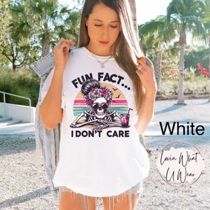 May include: White t-shirt with a graphic of a skeleton with flowers in its hair and the text "Fun Fact... I don't care".