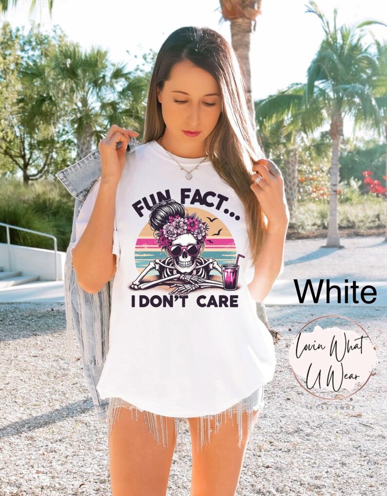 May include: White t-shirt with a graphic of a skeleton with flowers in its hair and the text "Fun Fact... I don't care".