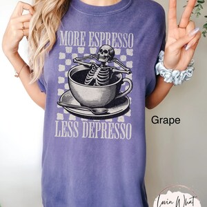 May include: Purple t-shirt with a graphic of a skeleton in a coffee cup. The text on the shirt reads "More Espresso Less Depresso" and "Grape".