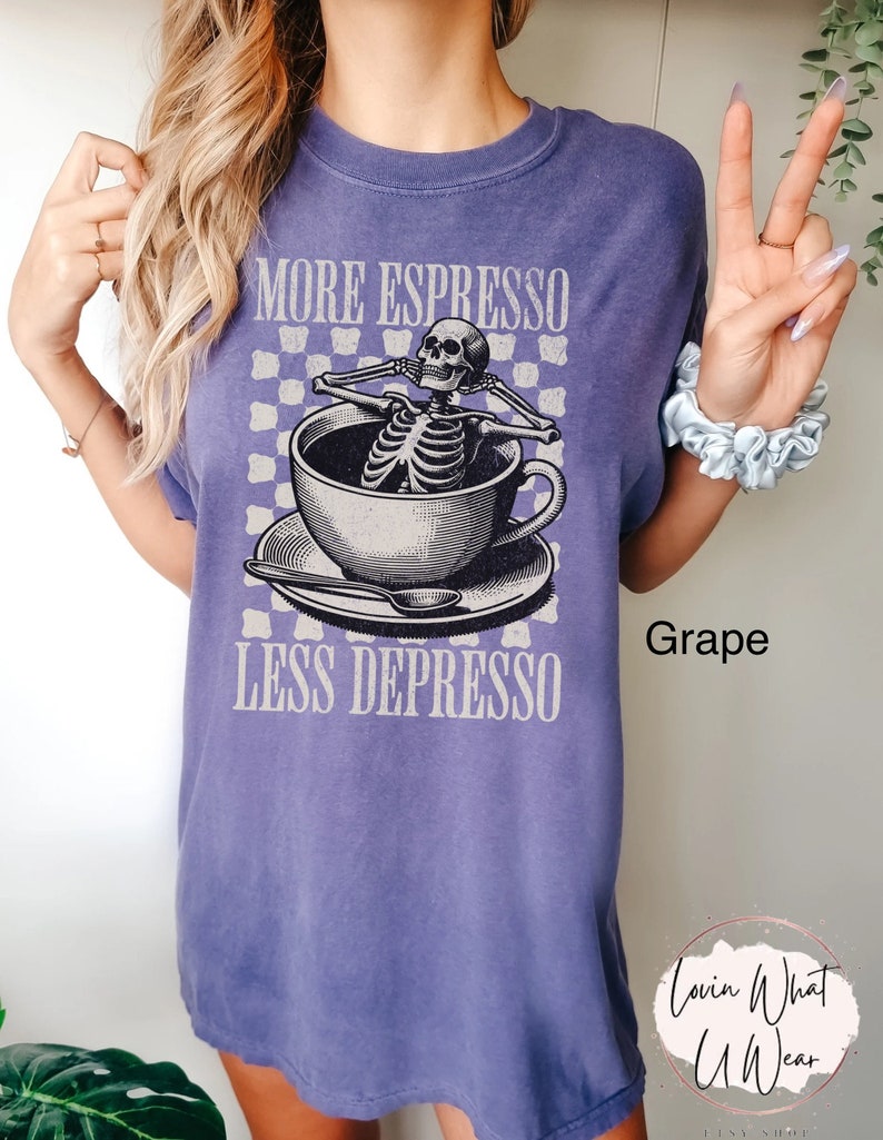 May include: Purple t-shirt with a graphic of a skeleton in a coffee cup. The text on the shirt reads "More Espresso Less Depresso" and "Grape".