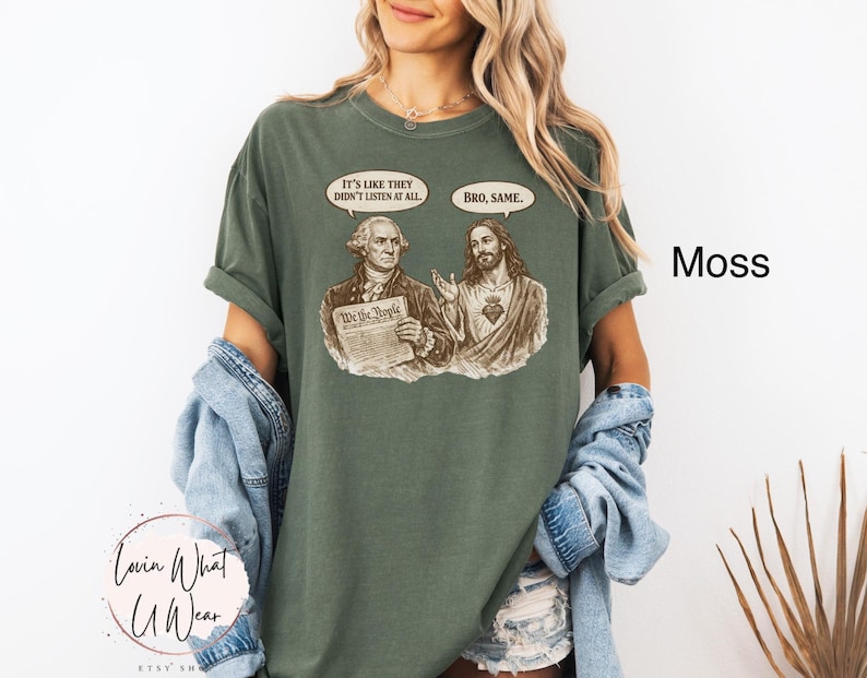 Może przedstawiać: Zielona koszulka w kolorze mchu z grafiką George'a Washingtona i Jezusa z dymkami. Washington trzyma dokument z napisem "We the People". Dymki m&oacute;wią "It's like they didn't listen at all" i "Bro, same."