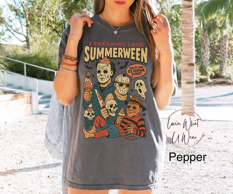 May include: Dark grey t-shirt featuring the text "I FREAKING LOVE SUMMERWEEN" and a graphic of horror movie characters with ice cream. The shirt also has the text "CAN'T GET SOME ICE SCREAM PLEASE?"