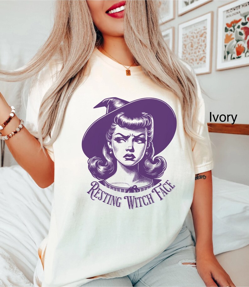May include: A white t-shirt with a purple illustration of a witch with the text "Resting Witch Face".