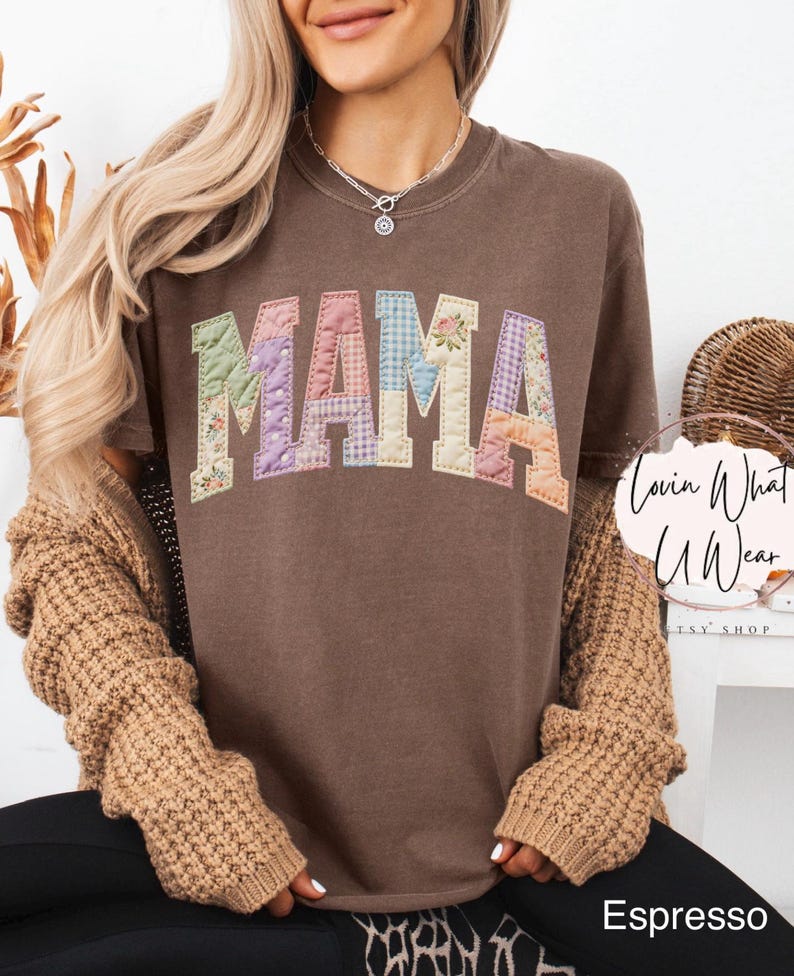 Puede incluir: Camiseta color espresso con la palabra "MAMA" en letras de patchwork. Las letras est&aacute;n hechas de varias telas florales y estampadas. La camiseta es de la tienda Etsy "Lovin What U Wear".