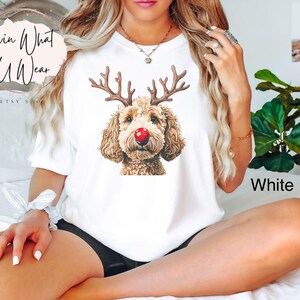 K&ouml;nnte beinhalten: Wei&szlig;es T-Shirt mit einem braunen Hund mit Rentiergeweih und roter Nase. Der Text "White" ist in der rechten unteren Ecke des Bildes sichtbar.
