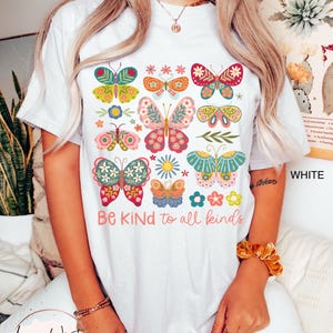 May include: White t-shirt with a colorful butterfly design and the text "Be Kind to all kinds".