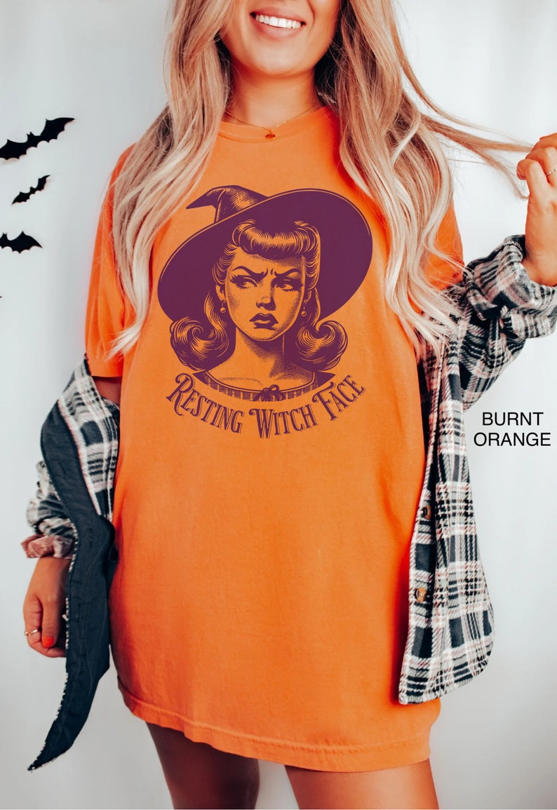 May include: A burnt orange t-shirt with a vintage illustration of a witch with a purple hat and the text "Resting Witch Face".