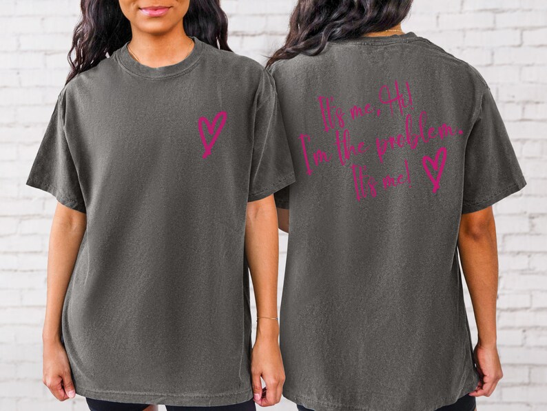 May include: A dark gray t-shirt with a pink heart on the front and the text "It's me, I'm the problem. It's me!" on the back.