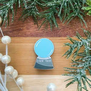 Könnte beinhalten: Eine blaue Glaskugel auf einem grauen Sockel mit dem Text "FKA 1121" auf dem Sockel. Die Kugel steht auf einer Holzoberfläche.