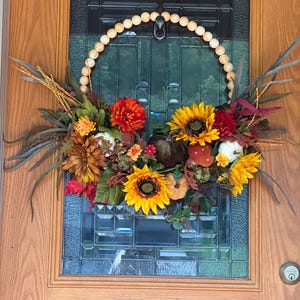 Fall beaded wreath that brings afresh new look to your fall . Beaded wreath with large sunflowers and fall foliage.