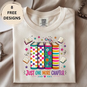 May include: A cream-colored t-shirt featuring a graphic of four colorful books with polka dot, checkerboard, floral, and striped patterns. Above the books are small open books and glasses. Below the books is the text "JUST ONE MORE CHAPTER".