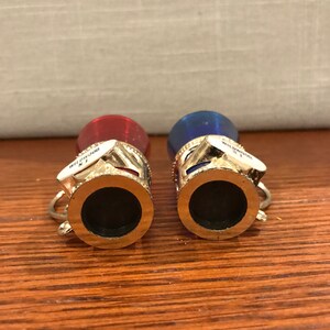 May include: Two miniature souvenir shot glasses with gold rims. The glasses are red and blue with white accents. The glasses have the words "Wildwood N.J." printed on them.