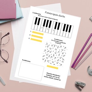 Könnte beinhalten: Ein Musikarbeitsblatt mit einem Klaviertastaturdiagramm und Noten, zusammen mit Bleistiften, Scheren und anderen Schreibwaren. Der Text enthält "Patstavigais darbs" und "Luzdevums".
