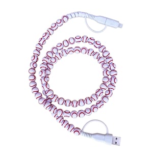 May include: A white charging cable featuring a series of small, spherical beads designed to resemble baseballs, each with white surfaces and red stitching patterns. The cable includes white plastic connectors at both ends for device charging.