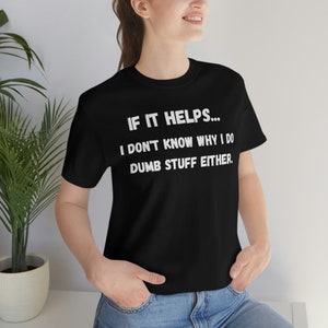 May include: Black t-shirt with the text "IF IT HELPS... I DON'T KNOW WHY I DO DUMB STUFF EITHER" in white. The shirt is a crew neck style.