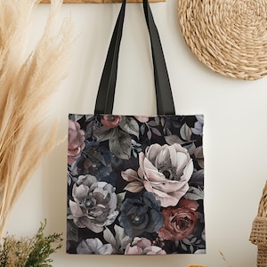May include: Black tote bag featuring a floral pattern with large, stylized flowers in shades of pink, gray, and burgundy. The flowers are set against a dark background with black handles.