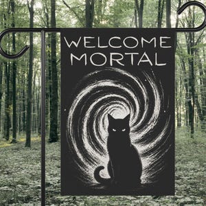 May include: A rectangular garden flag featuring a black background with the white text WELCOME MORTAL at the top. Below the text is a white swirling vortex graphic centered behind a solid black silhouette of a cat with glowing white eyes.
