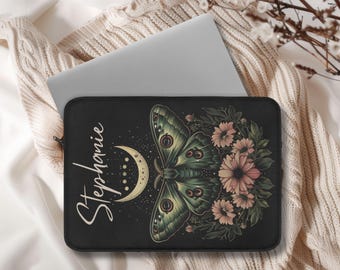 May include: Black laptop sleeve featuring a detailed illustration of a moth with green and yellow wings, a crescent moon, and pink flowers. The name "Stephanie" is written in cursive. The sleeve is designed to protect a laptop.