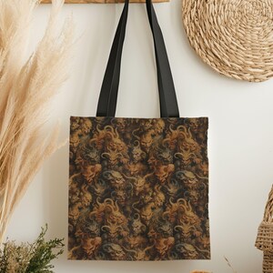 May include: A tote bag with a repeating pattern of grotesque faces in shades of brown, green, and gold. The bag has black handles and is hanging against a white wall with decorative elements.