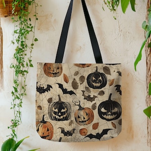 May include: A Halloween-themed tote bag with black handles. The bag features a repeating pattern of jack-o'-lanterns, bats, and leaves on a beige background with spiderwebs. The pumpkins are orange and black.