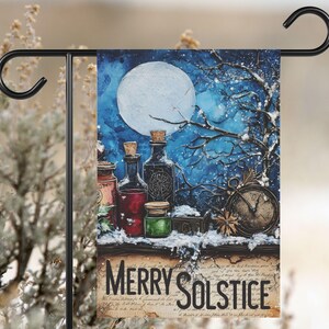May include: A garden flag featuring a winter solstice design. The flag displays a full moon, bottles, a clock, and the words "Merry Solstice." The color palette includes blues, browns, and greens.