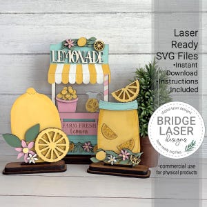 May include: Wooden laser-cut lemonade stand decor with a yellow and white striped awning, a large lemon, and a mason jar filled with lemon slices. The text "LEMONADE" and "FARM FRESH Lemons" are visible. Includes the text "Laser Ready SVG Files".