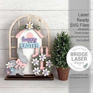 Puede incluir: Decoración de Pascua de madera con un conejito, una casita para pájaros y una corona. La casita para pájaros muestra "happy EASTER" en colores pastel. El conejito tiene un lazo rosa y detalles florales. La corona está adornada con flores blancas y moradas.