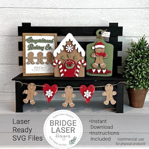 Könnte beinhalten: Ein Set an lasergeschnittenen Lebkuchen-Weihnachtsdekorationen. Das Set beinhaltet ein Lebkuchenhaus, ein Lebkuchenmann-Brett, ein Lebkuchenmann-Banner und ein Schild mit der Aufschrift "Gingerbread Baking Co.".