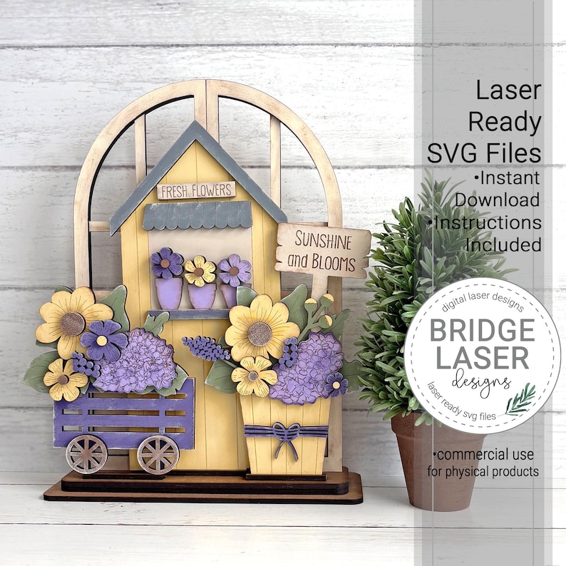 May include: A wooden decorative piece featuring a yellow house with a gray roof, adorned with purple and yellow flowers. A small sign reads "Sunshine and Blooms." The design includes a flower cart and a flower pot, with the text "Fresh Flowers" above the house.