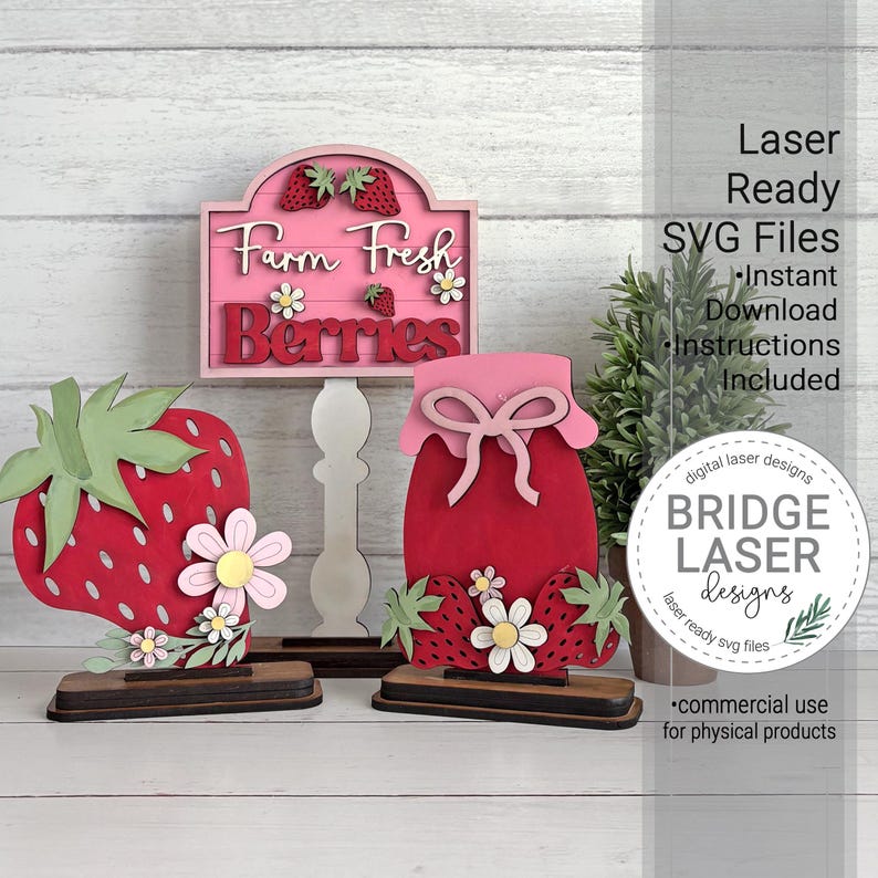 May include: Wooden strawberry-themed decorations. Includes a sign that reads "Farm Fresh Berries", a strawberry, and a jar-shaped item. The items are red, pink, green, and white. The sign and jar have a bow on top. The items are on a wooden base.