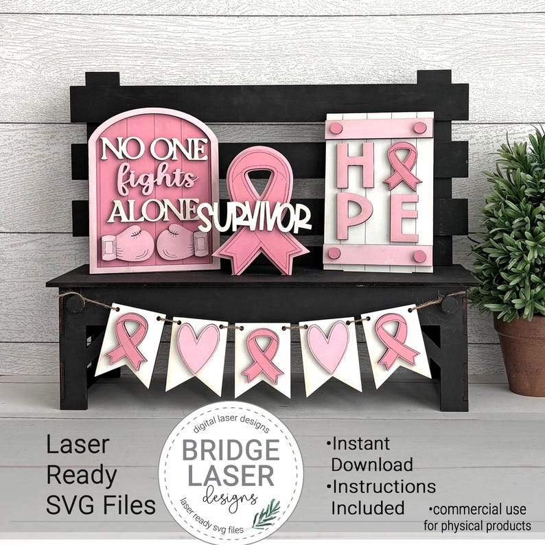 Peut inclure: Un banc en bois noir pr&eacute;sente des d&eacute;corations roses et blanches d&eacute;coup&eacute;es au laser. Les d&eacute;corations comprennent une enseigne avec les mots "NO ONE FIGHTS ALONE", un ruban rose et une enseigne avec le mot "HOPE". Une banni&egrave;re avec des rubans et des c&oelig;urs roses est suspendue en dessous.