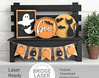 Puede incluir: Un banco de madera negro exhibe decoraciones temáticas de Halloween. Se presenta un fantasma enmarcado, un letrero con "boo!" y murciélagos, y una silueta de gato contra una luna amarilla. Una pancarta con calabazas y calderos cuelga debajo. El texto "Laser Ready SVG Files".