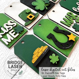 May include: Laser cut SVG files for St. Patrick's Day tags. The designs include a shamrock, a pot of gold, a horseshoe, a leprechaun hat, and the text "Kiss Me".