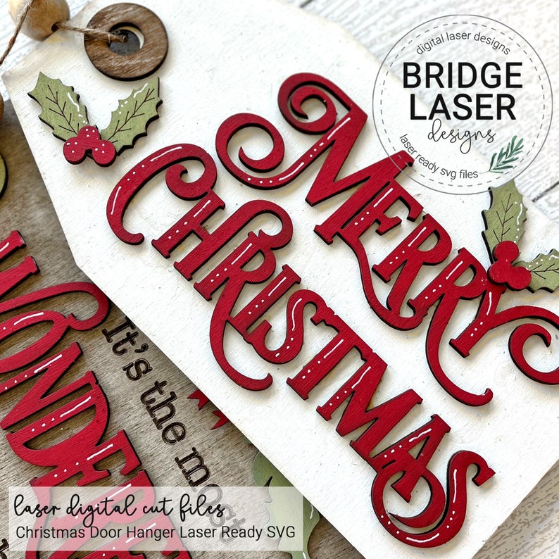 May include: A white wooden door hanger sign featuring red laser-cut lettering that reads Merry Christmas. The sign is decorated with green holly leaves and red berries. A circular wooden bead and a dark brown wooden ring are attached at the top.