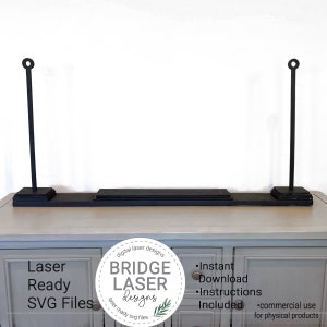 May include: Black laser-cut shelf with two vertical supports, each topped with a circular design. The shelf sits on a light-colored cabinet. The image includes text that reads "Laser Ready SVG Files" and "Bridge Laser Designs."