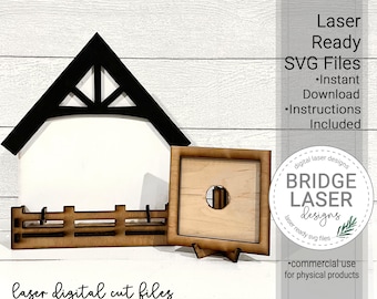 May include: Laser cut file design for a house and frame. The house has a black roof and a white frame. The frame is a square with a round hole in the center. The design is for interchangeable pieces, sold separately. The text "laser digital cut files" is at the bottom of the image. The text "Interchangeable House and Frame" is below the text "laser digital cut files". The text "Interchangeable Pieces Sold Separately" is below the text "Interchangeable House and Frame".