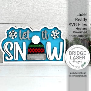 May include: Let it snow wooden sign with a white background and blue woodgrain. The sign features a white beanie with red and green stripes and a white pom pom. The sign is laser cut and ready to be assembled.