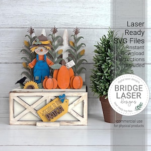 May include: A multi-layered wooden craft display featuring a scarecrow in blue overalls, orange pumpkins, and corn stalks in front of a white picket fence. A yellow tag reads Welcome to the PATCH. Text includes Laser Ready SVG Files.