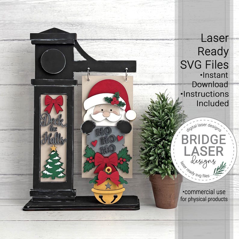 May include: A black wooden sign stand featuring a hanging rectangular plaque with a layered Santa Claus design, the text HO HO HO, a red bow, and a yellow bell. The stand includes a vertical panel with a red bow, the text Deck the Halls, and a tree.