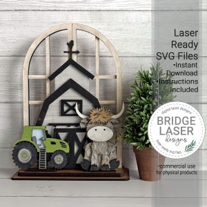 Peut inclure: Décoration en bois sur le thème de la ferme, avec une grange, un tracteur et une vache des Highlands. La grange est blanche et noire, avec une croix. Le tracteur est vert. La vache des Highlands a un visage souriant. Le texte "Laser Ready SVG Files" est visible.