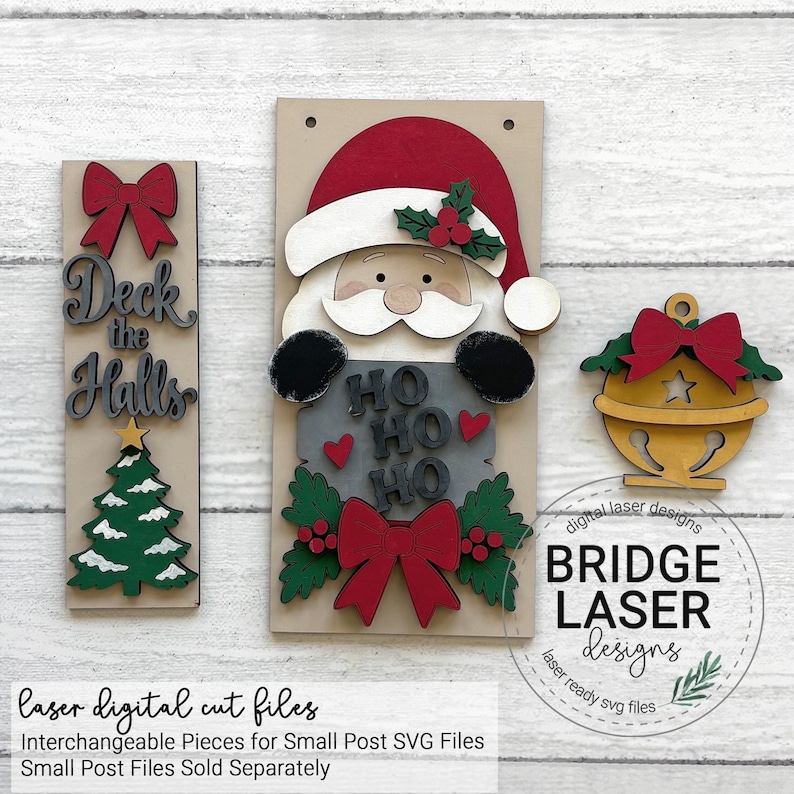 May include: A set of three wooden laser-cut Christmas decorations including a vertical sign with the text Deck the Halls, a Santa Claus figure holding a sign with the text HO HO HO, and a gold bell ornament, all featuring red bows and green holly.