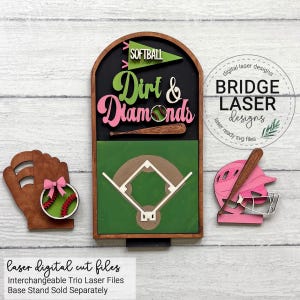 May include: A wooden arched sign featuring the text Softball Dirt & Diamonds with a green pennant, a baseball bat, and a baseball field graphic. Included are a wooden glove with a softball and a pink batting helmet with a bat and face mask.