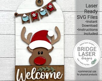 May include: A laser-cut wooden welcome sign featuring a reindeer with a red Santa hat and a banner of hot chocolate mugs. The sign says "Welcome" in a decorative font.