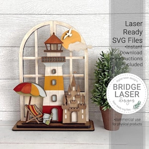 Peut inclure: Décoration en bois sur le thème de la plage, avec un phare, un château, un parasol et une chaise. Le phare est blanc, jaune et rouge. Le texte "Laser Ready SVG Files" et "Bridge Laser Designs" est inclus.