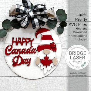 May include: A red and white gnome holding a red maple leaf with the words "Happy Canada Day" in red letters on a white round wooden sign.