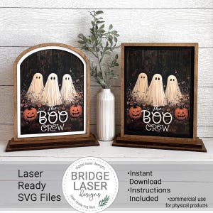 May include: Two wooden Halloween signs with the text "The Boo Crew". Each sign features three white ghost figures, two orange pumpkins, and a dark background. One sign has an arched top, the other is rectangular.