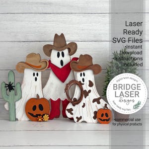 May include: Three white ghost cutouts wearing brown cowboy hats. The center ghost wears a red bandana and red boots. The right ghost has brown cow-print spots and holds a brown lasso. A green cactus with a black spider and two orange pumpkins are included.